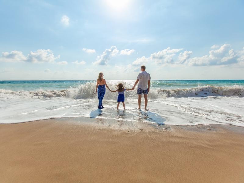 A family walking hand in hand at the water's edge