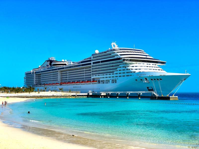 A cruise ship anchored off a turquoise Caribbean beach